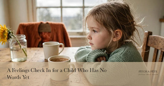 A young girl in a green jumper resting her chin on her folded arms at a kitchen table, the quiet moment for a feelings check in
